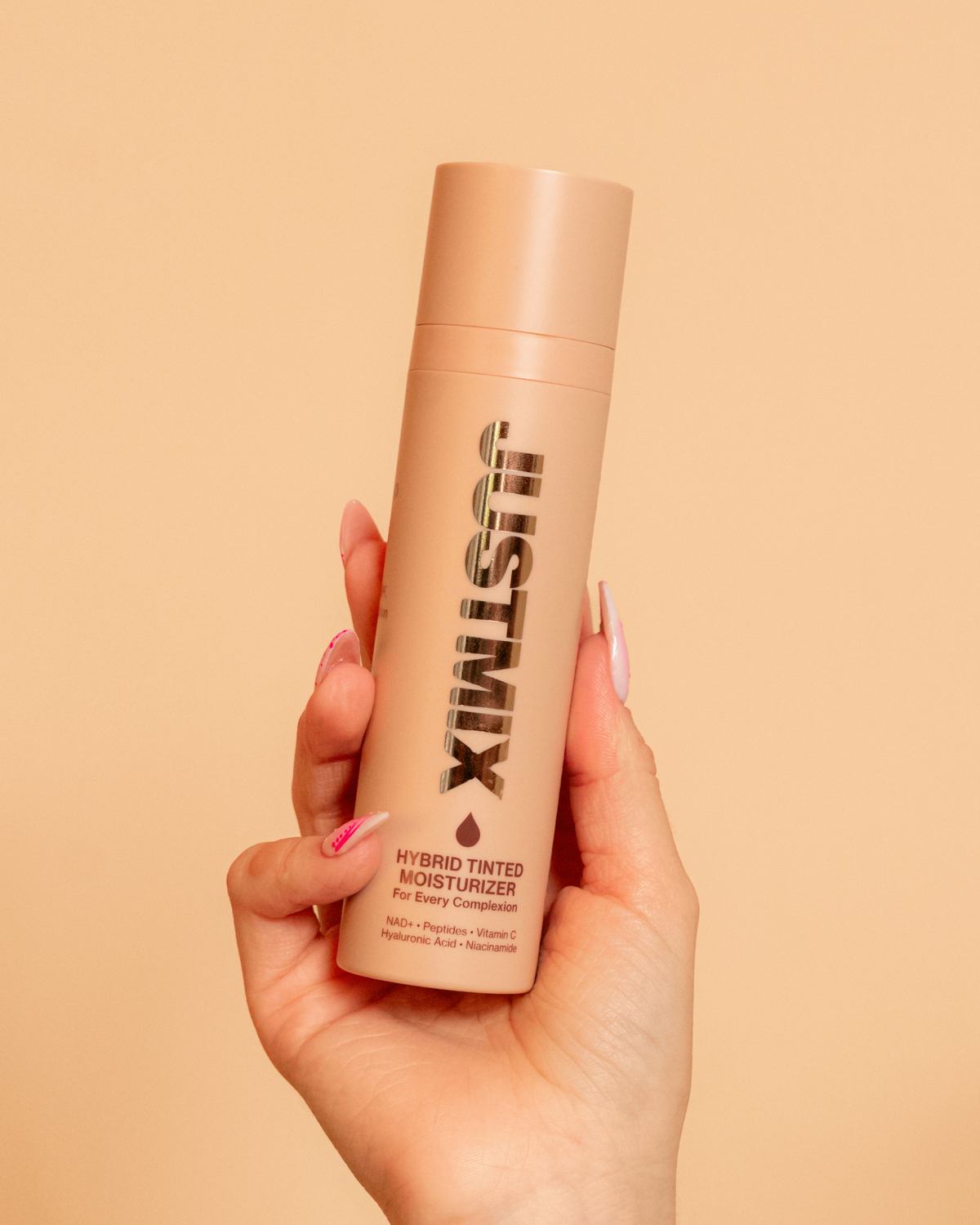 Hand holding a bottle of JUSTMIX Hybrid Tinted Moisturizer